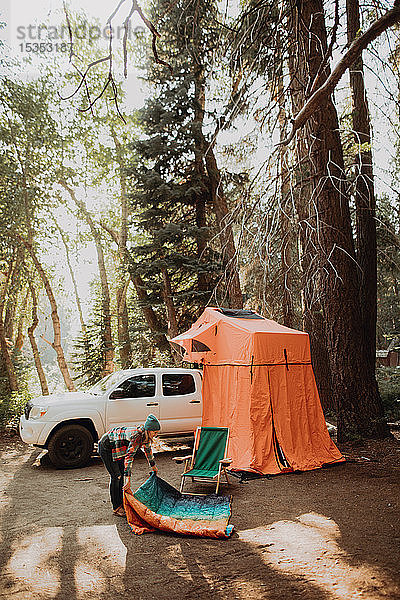 Mittelgroße erwachsene Frau entfaltet Schlafsack auf einem Waldcampingplatz  Mineral King  Kalifornien  USA