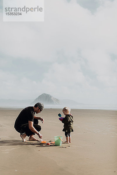 Vater und Kleinkind spielen mit Sand am Strand  Morro Bay  Kalifornien  Vereinigte Staaten