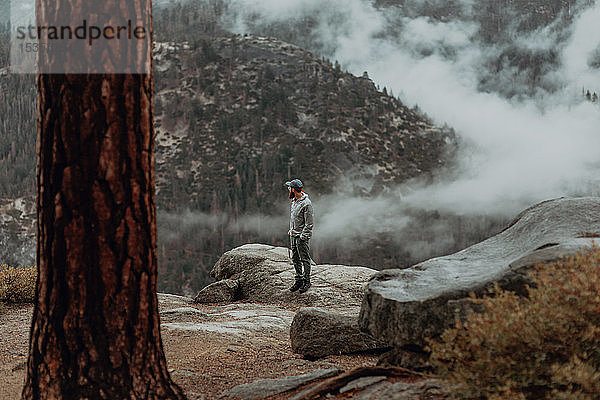 Wanderer genießt Aussicht auf nebeldurchzogenes Tal  Yosemite National Park  Kalifornien  Vereinigte Staaten