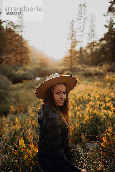 Junge Frau in Stetson blickt im ländlichen Tal bei Sonnenuntergang zurück  Mineral King  Kalifornien  USA