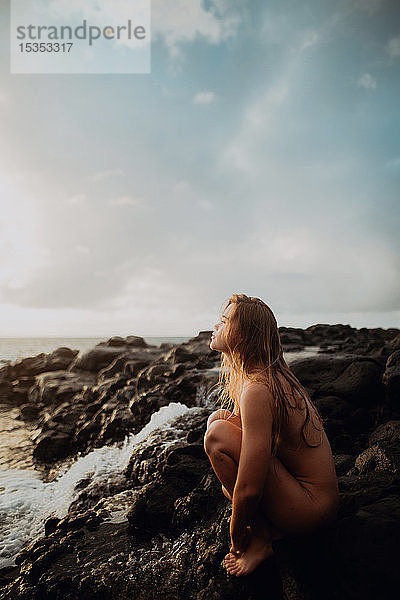 Nackte Frau sitzt auf Felsen am Meer  Princeville  Hawaii  USA