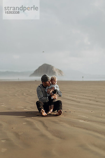 Vater und Kleinkind am Strand sitzend  Morro Bay  Kalifornien  Vereinigte Staaten