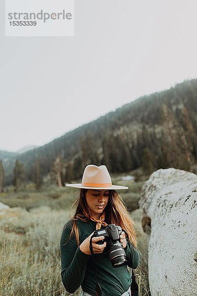 Junge Frau in Stetson begutachtet Fotos auf einer Digitalkamera im ländlichen Tal  Mineral King  Kalifornien  USA