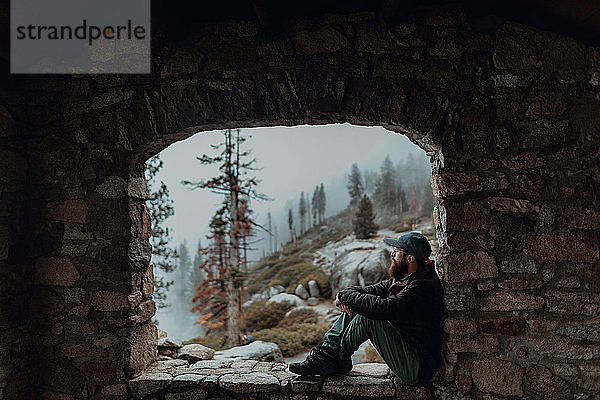 Wanderer genießt Aussicht auf nebliges Tal auf Felsvorsprung  Yosemite National Park  Kalifornien  Vereinigte Staaten