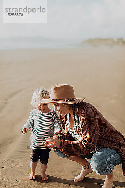 Mutter und Kleinkind spielen am Strand