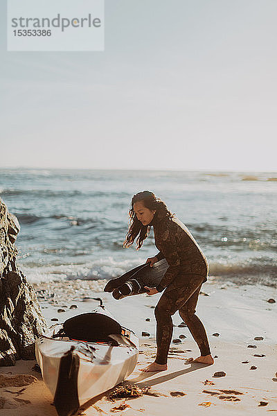 Frau setzt Flossen in Kajak am Strand  Big Sur  Kalifornien  Vereinigte Staaten