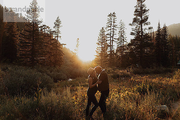 Schwangere Paare im mittleren Erwachsenenalter stehen sich bei Sonnenuntergang in einem ländlichen Tal gegenüber  Mineral King  Kalifornien  USA