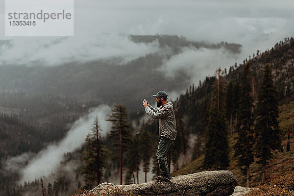 Wanderer beim Fotografieren der Ansicht des nebelverhangenen Tals  Yosemite National Park  Kalifornien  Vereinigte Staaten