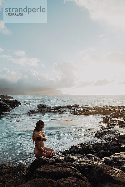 Nackte Frau sitzt auf Felsen am Meeresbecken  Princeville  Hawaii  USA