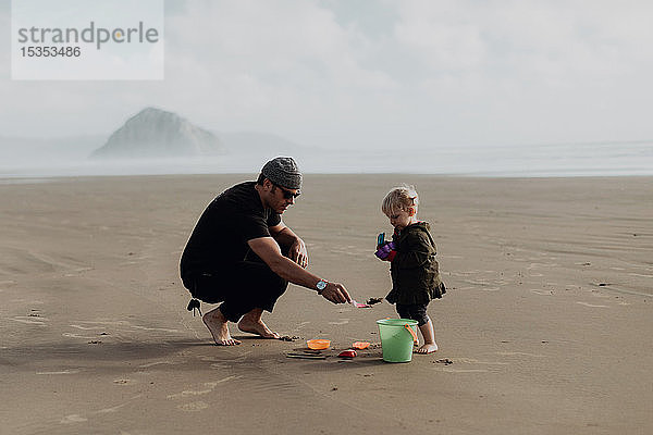 Vater und Kleinkind spielen mit Sand am Strand  Morro Bay  Kalifornien  Vereinigte Staaten