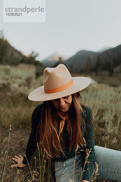 Junge Frau in Stetson  die im ländlichen Tal sitzt und hinunterblickt  Mineral King  Kalifornien  USA