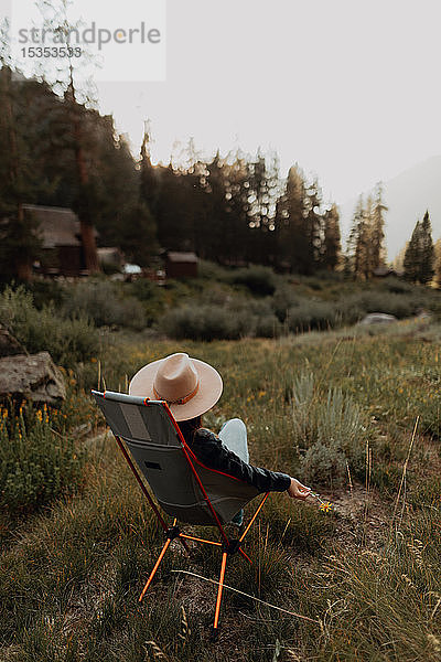 Junge Frau in Stetson entspannt auf einem Liegestuhl im ländlichen Tal  Rückansicht  Mineral King  Kalifornien  USA