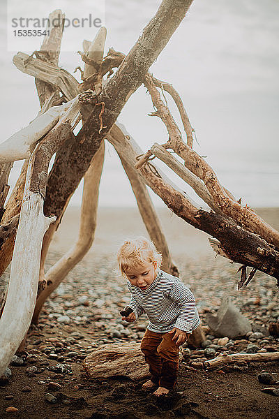 Kleinkind spielt neben Wigwam am Strand