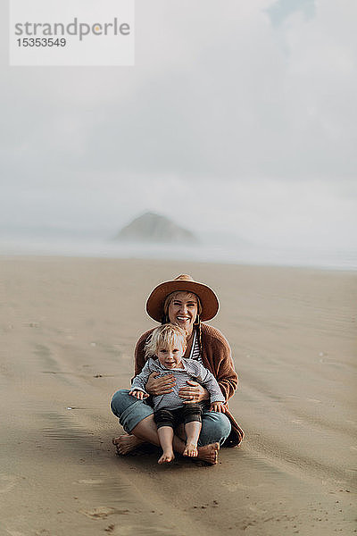 Mutter und Kleinkind am Strand sitzend  Morro Bay  Kalifornien  Vereinigte Staaten