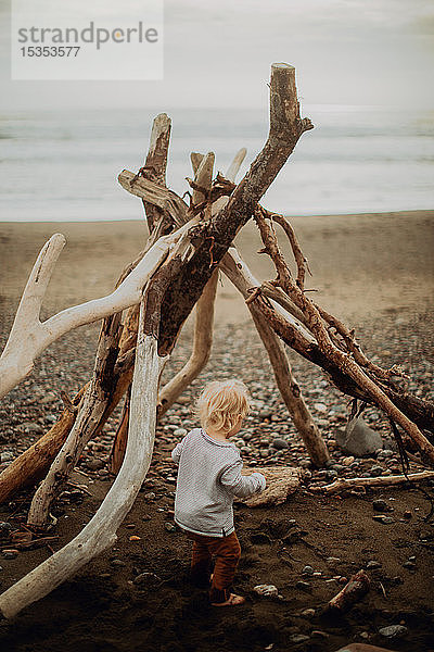 Kleinkind spielt neben Wigwam am Strand