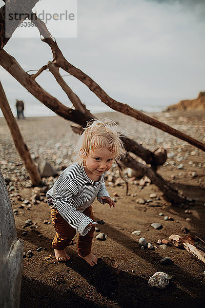 Kleinkind spielt neben Wigwam am Strand