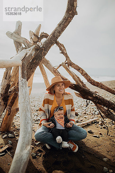 Mutter und Baby sitzen im Wigwam am Strand