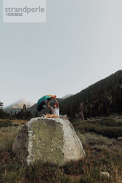 Junger Mann sitzt oben auf einem Felsblock im ländlichen Tal  Mineral King  Kalifornien  USA