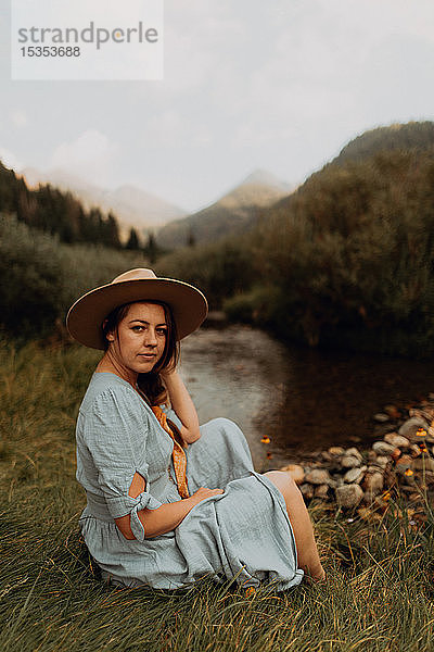 Junge Frau in Stetson am ländlichen Fluss sitzend  Porträt  Mineral King  Kalifornien  USA