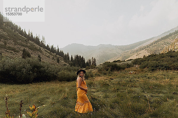 Schwangere Frau im mittleren Erwachsenenalter in orangefarbenem Maxikleid im ländlichen Tal  Porträt  Mineral King  Kalifornien  USA