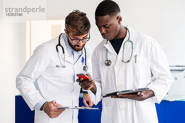 Ärzte mit Smartphone an der Krankenhausrezeption
