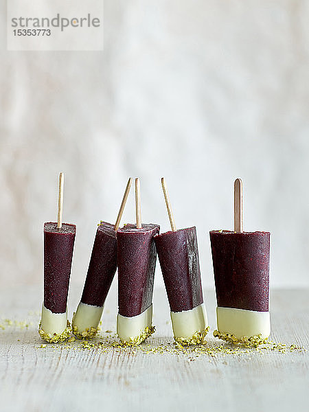 Dreifarbige Eislollies in einer Reihe auf Tisch  weißer Hintergrund