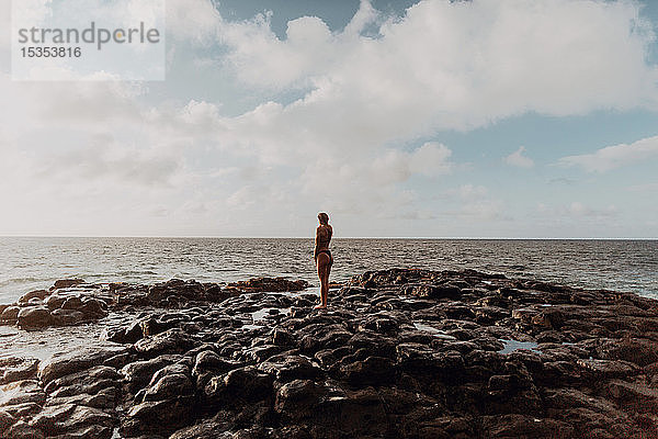 Auf Felsen am Meer stehender Schwimmer  Princeville  Hawaii  USA