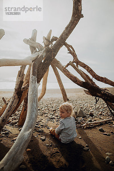 Kleinkind sitzt im Wigwam am Strand