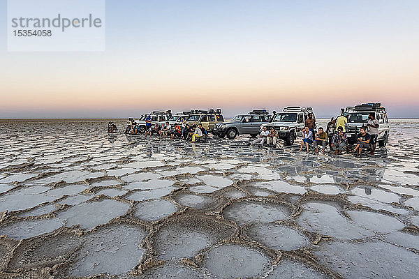Touristen vor einem Fahrzeug mit Allradantrieb auf den Salzebenen des Karum-Sees (Assale-See) bei Sonnenuntergang  Danakil-Senke; Afar-Region  Äthiopien