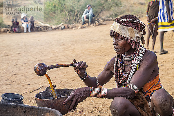 Hamer-Frau bei der Zubereitung eines zeremoniellen Getränks während einer Stiersprungzeremonie  mit der ein Junge in die Männlichkeit eingeführt wird  im Dorf Asile  Omo-Tal; Region der südlichen Nationen und Völker  Äthiopien