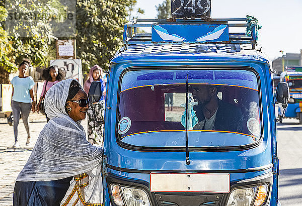Frau in einer Auto-Rikscha  die durch das Fenster mit dem Fahrer spricht; Wukro  Region Tigray  Äthiopien