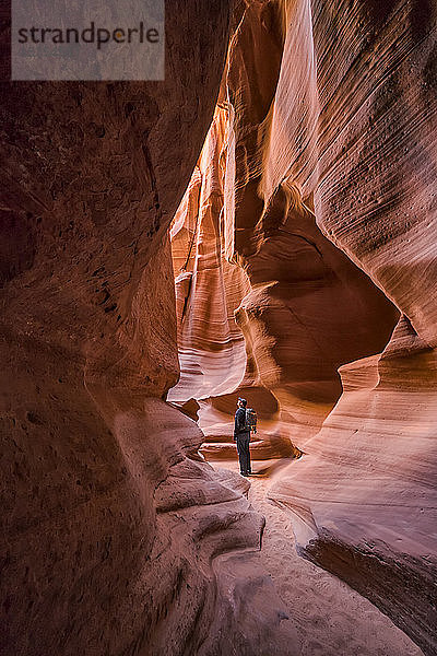 Mann steht in einem Slot Canyon  bekannt als Canyon X  in der Nähe von Page; Arizona  Vereinigte Staaten von Amerika