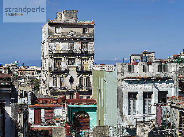 Ein altes Wohngebäude mit verwitterter Fassade vor blauem Himmel; Havanna  Kuba