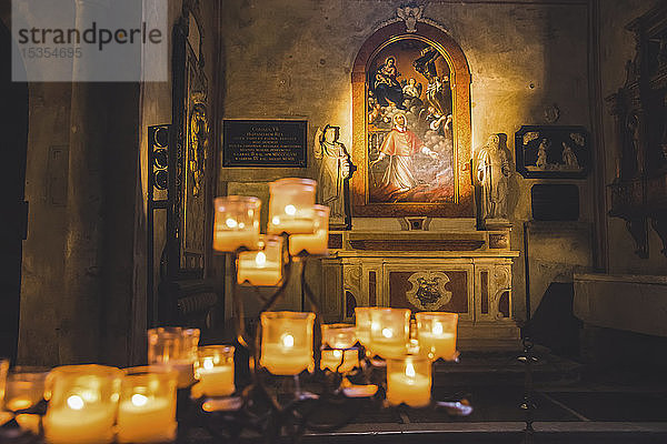 Angezündete Kerzen und Kunstwerke in einer Kathedrale; Italien