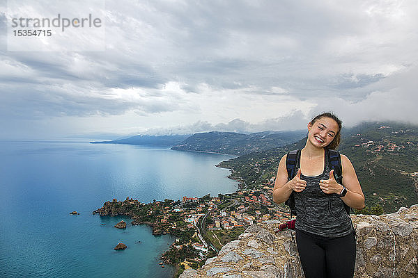 Eine junge Touristin steht auf einem Aussichtspunkt an der Mittelmeerküste; Cefalu  Sizilien  Italien