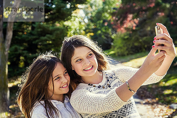 Zwei Schwestern machen ein Selbstporträt von sich während eines Familienausflugs in einem Stadtpark an einem warmen Herbsttag: Edmonton  Alberta  Kanada