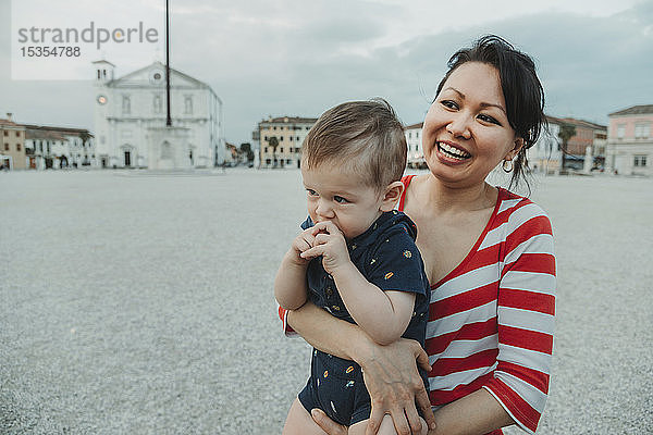 Eine Frau hält einen kleinen Jungen am Strand; Italien