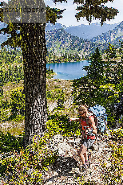 Rucksacktouristin auf dem High Divide Trail mit Blick auf den Lunch Lake im Sommer  Seven Lakes Basin  Olympic National Park  Olympic Mountains; Washington  Vereinigte Staaten von Amerika