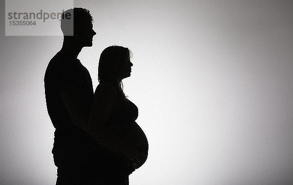 Silhouette eines Paares in einem Studio  das ein Baby erwartet  wobei die Mutter schon weit in ihrer Schwangerschaft ist; Edmonton  Alberta  Kanada