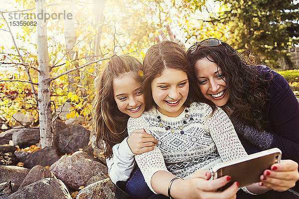 Eine Mutter und ihre beiden Töchter machen ein Selbstporträt  während sie sich bei einem Familienausflug in einem Stadtpark an einem warmen Herbsttag ausruhen; Edmonton  Alberta  Kanada