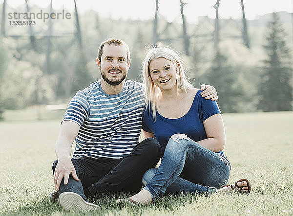 Porträt eines Paares in einem Park  das im Gras sitzt; Edmonton  Alberta  Kanada