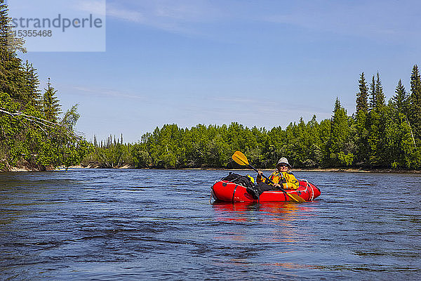 Rucksacktouristin entspannt sich auf einem sanften Abschnitt des Charley River  Yukonâ€ Charley Rivers National Preserve; Alaska  Vereinigte Staaten von Amerika