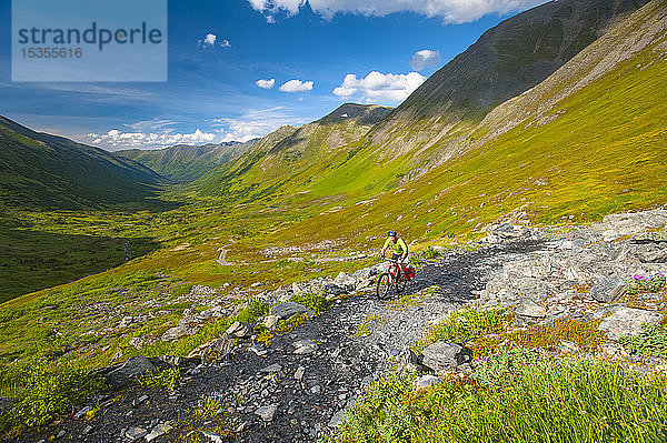 Ein Mann fährt mit seinem Mountainbike auf der Palmer Valley Road in der Nähe von Hope  Alaska  an einem sonnigen Sommertag in Süd-Zentral-Alaska; Alaska  Vereinigte Staaten von Amerika