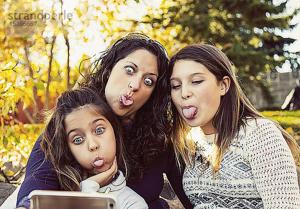 Eine Mutter und ihre beiden Töchter machen ein Selbstporträt  während sie sich bei einem Familienausflug in einem Stadtpark an einem warmen Herbsttag ausruhen; Edmonton  Alberta  Kanada