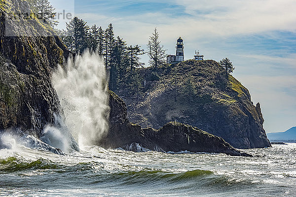 Eine Welle bricht an den Felsen unterhalb des Cape Disappointment North Head Lighthouse an der Mündung des Columbia River; Ilwaco  Washington  Vereinigte Staaten von Amerika