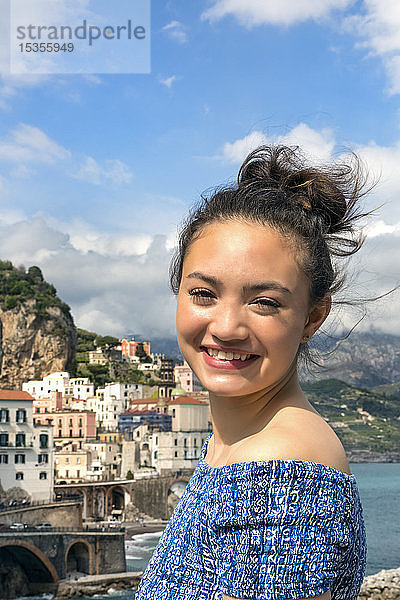 Eine junge Frau posiert mit dem Blick auf die Amalfiküste und das Mittelmeer im Hintergrund; Amalfi  Italien