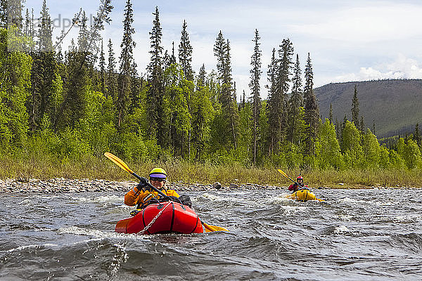 Zwei Packrafterinnen  die im Sommer einen Nebenfluss des Charley River befahren  Yukonâ€ Charley Rivers National Preserve; Alaska  Vereinigte Staaten von Amerika
