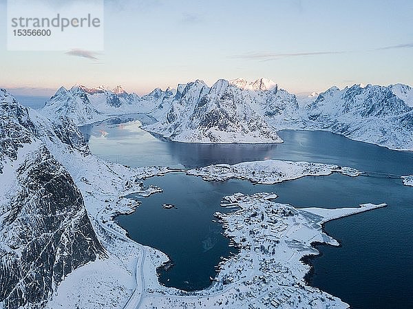 Verschneite Berge am Fjord mit Ort Reine  Sonnenaufgang  Drohnenaufnahme  Lofoten  Norwegen  Europa