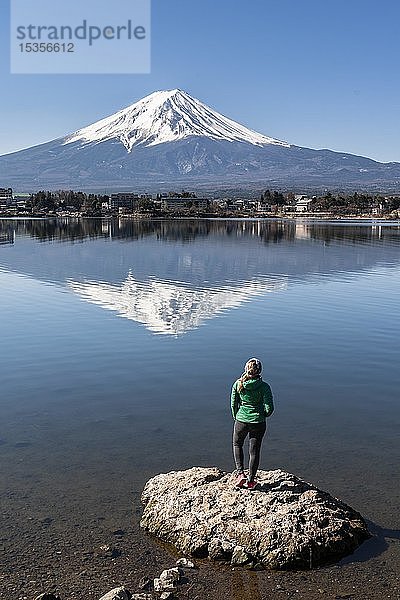 Junge Frau steht auf einem Stein im Wasser  Kawaguchi-See  hinterer Vulkan Mt. Fuji  Präfektur Yamanashi  Japan  Asien