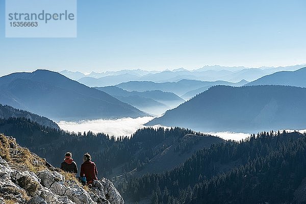 Wanderer rasten auf dem Gipfel  Panoramablick auf die Alpen vom Gipfel des Breitensteins  Hochnebel über dem Tal  Fischbachau  Bayern  Deutschland  Europa